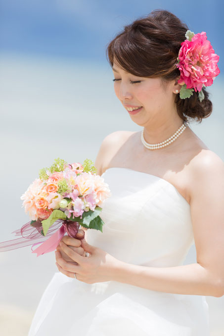 沖縄のビーチフォトのイメージにピッタリの濃いピンクのヘアアクセサリーをあしらったヘアスタイル