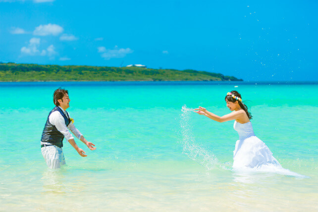 青空とエメラルドグリーンの海を眺めながらゆったりと結婚写真を撮影