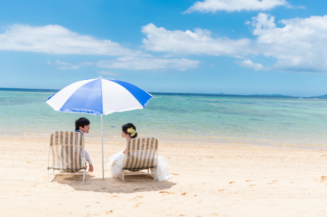 ふたり仲良く沖縄の海でビーチパラソル 沖縄ウェディングオンライン